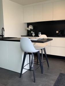 a kitchen with two white chairs and a counter with wine glasses at Ultra-luxury penthouse with a generous terrace and breathtaking sea view T71 in Ostend