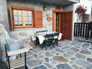 a patio with a table and chairs on a stone floor at Casa Anna - Montemezzo in Bugiallo
