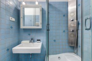 a blue tiled bathroom with a sink and a mirror at Liberty Square Apartment in Budapest