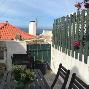 a patio with two benches and a fence with flowers at Azenhas do Mar Cottage in Sintra