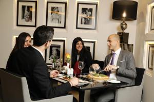 a group of people sitting around a table in a restaurant at Royal Tulip Achrafieh in Beirut