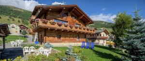 a log cabin with a balcony and tables and chairs at Elisa Bait Giobbe in Livigno