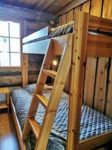 a bunk bed in a log cabin with a ladder at Rukanhelmi jr. in Ruka