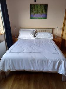 Una cama con sábanas blancas y almohadas en un dormitorio en Benbulben View F91YN96 en Sligo