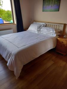 1 cama blanca grande en un dormitorio con ventana en Benbulben View F91YN96 en Sligo