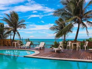 een zwembad met stoelen en palmbomen en de oceaan bij Flat da Praia Natal in Natal