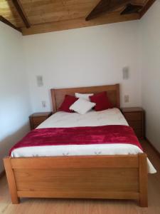 a bedroom with a large bed with red pillows at Quintinha dos Emigrantes in Cujó