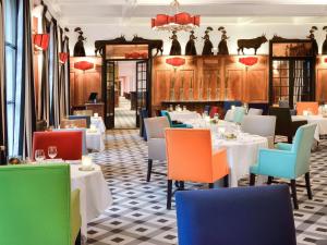 a restaurant with white tables and colorful chairs at Hôtel & Spa Jules César Arles - MGallery Hotel Collection in Arles