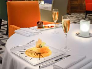 a table with a plate of food and glasses of champagne at Hôtel & Spa Jules César Arles - MGallery Hotel Collection in Arles