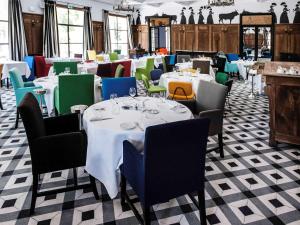 une salle à manger avec des tables blanches et des chaises colorées dans l'établissement Hôtel & Spa Jules César Arles - MGallery Hotel Collection, à Arles