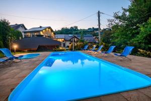 a swimming pool with blue chairs and a house at Osada nad Słotwinką in Krynica Zdrój