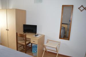 a bedroom with a desk with a television and a mirror at GARNI ANNA in Besenello