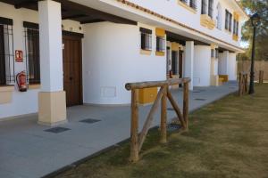 a building with a wooden sign in front of it at La Cancela Apartamentos Turísticos in El Rocío