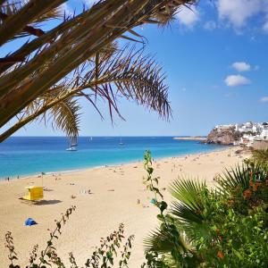 a beach with a bunch of people in the water at Casa Árida, Morro Jable in Morro del Jable