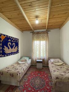 twee bedden in een kamer met een raam en een tapijt bij Guest House Guljan in Bokonbayevo