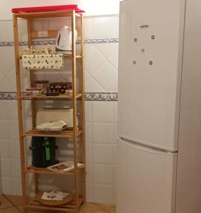 a kitchen with a white refrigerator and a wooden shelf at Amarelaje in Serra de El-Rei