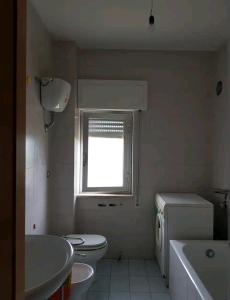 baño con aseo y lavabo y ventana en Appartamento con vista sul mare, en Marina di Gioiosa Ionica