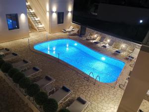 an overhead view of a large swimming pool with white chairs at Anemos Villas in Mitika