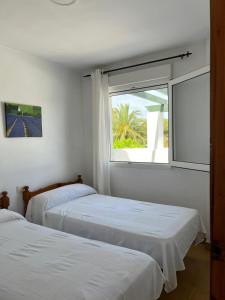 two beds in a room with a window at Atlanterra Pueblo Donkey - Piscina, parking in Zahara de los Atunes