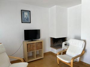 a living room with a tv and a chair at Atlanterra Pueblo Donkey - Piscina, parking in Zahara de los Atunes