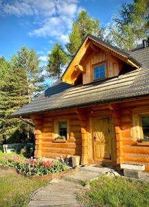 a log cabin with a door and flowers in front of it at Dom z drzew in Istebna