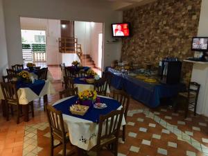 une salle à manger avec des tables et des chaises bleues et une télévision dans l'établissement B&B Hollywood - Parcheggio Privato, à Porto Cesareo