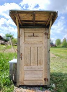 um barracão de madeira com uma porta de madeira num campo em Gula Vagnen em Hörby