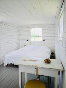 um quarto branco com uma cama, uma mesa e uma janela em Gula Vagnen em Hörby