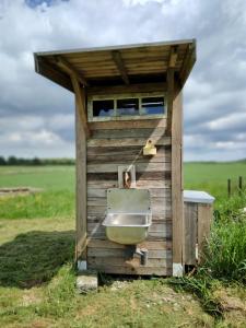 a wooden out house with a sink in a field at Gula Vagnen in Hörby