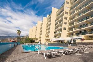a hotel swimming pool with lounge chairs and a building at Tranquil Beachside Stay - Atlantic Gardens Beach in Funchal