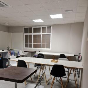 a classroom with tables and chairs and a white wall at Hostel Río Eo Albergue Ribadeo in Ribadeo