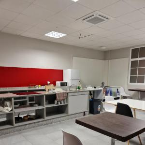 a kitchen with a counter and a red wall at Hostel Río Eo Albergue Ribadeo in Ribadeo