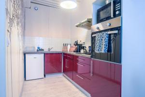 a kitchen with red cabinets and a microwave at L'HélleNid : Studio CONFORT Riom Centre in Riom