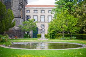 a fountain in the middle of a park in front of a building at L'HELLENID - Logement Spacieux Proche Cour d'appel Riom in Riom