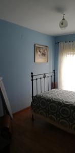 een blauwe slaapkamer met een bed en een raam bij Casa Herbellas in Cedeira