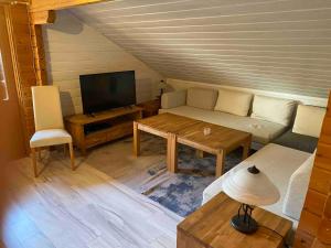 ein Wohnzimmer mit einem Sofa, einem Tisch und einem TV in der Unterkunft Eifelcottage in Ulmen