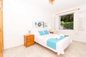 a white bedroom with a bed and a window at Casa Playa by Sonne Villas in Ferreries