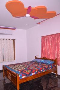 Schlafzimmer mit einem Bett und einem Deckenventilator in der Unterkunft YUGA GUEST HOUSE in Kuttālam