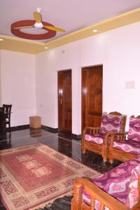 ein Wohnzimmer mit 2 Stühlen und einem Deckenventilator in der Unterkunft YUGA GUEST HOUSE in Kuttālam