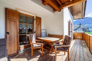 einen Holztisch und Stühle auf einer Holzterrasse in der Unterkunft Hof am Schloss Apartement Enzian in Montechiaro