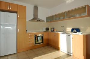 Una cocina con gabinetes de madera y un refrigerador blanco. en Villa Azucena by Sonne Villas, en Cala Galdana