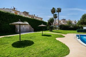a lawn with two umbrellas and a swimming pool at Espanhouse Rio Mar in Pilar de la Horadada