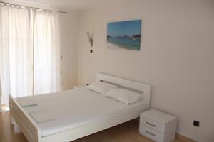 a white bedroom with a white bed and a window at Villa Nautica in Luštica