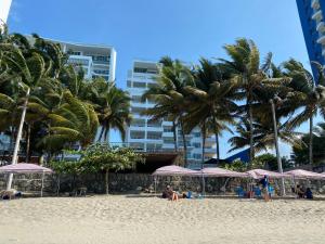 una playa con palmeras y sombrillas. en Suites de Lujo Playa Azul en Tonsupa