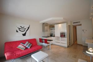 a living room with a red couch and a kitchen at Résidence Gray d'Albion 2P NAP558 in Cannes