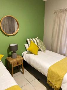Grünes Zimmer mit 2 Betten und einem Spiegel in der Unterkunft Gable Cottages No.4 Clarens in Clarens