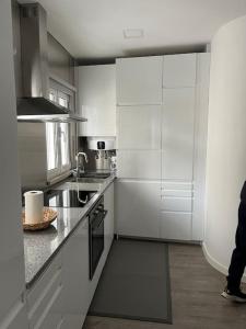 uma cozinha com armários brancos e electrodomésticos de aço inoxidável em Casa Mar Azul na Nazaré