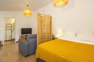 a bedroom with a yellow bed and a blue couch at Idylle - Charmant bungalow à 2 pas du lagon in La Saline les Bains