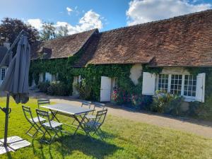 a table and chairs in front of a cottage at Le Moulin du Châtelier in Paulmy