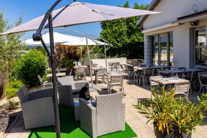 un patio con mesas, sillas y una sombrilla en Campanile Dijon Nord - Toison D'or, en Dijon